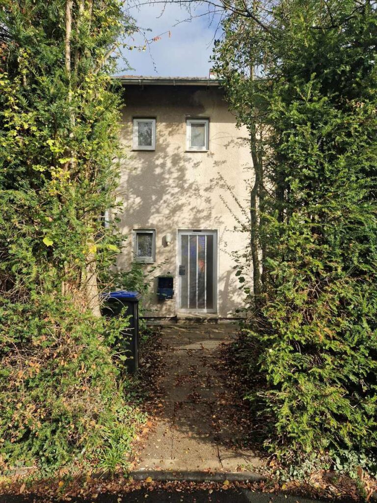Zweigeschossiges Wohnhaus mit Gartenweg und dichter Heckenbepflanzung